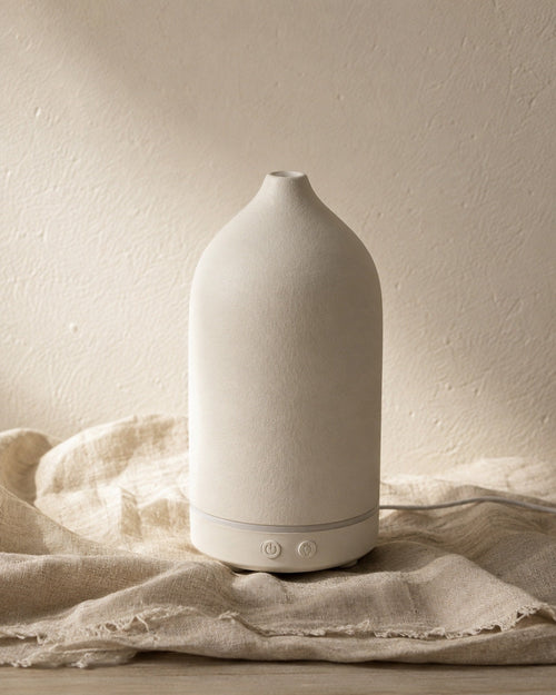 The Vagar diffuser standing on linen against a pale plaster wall