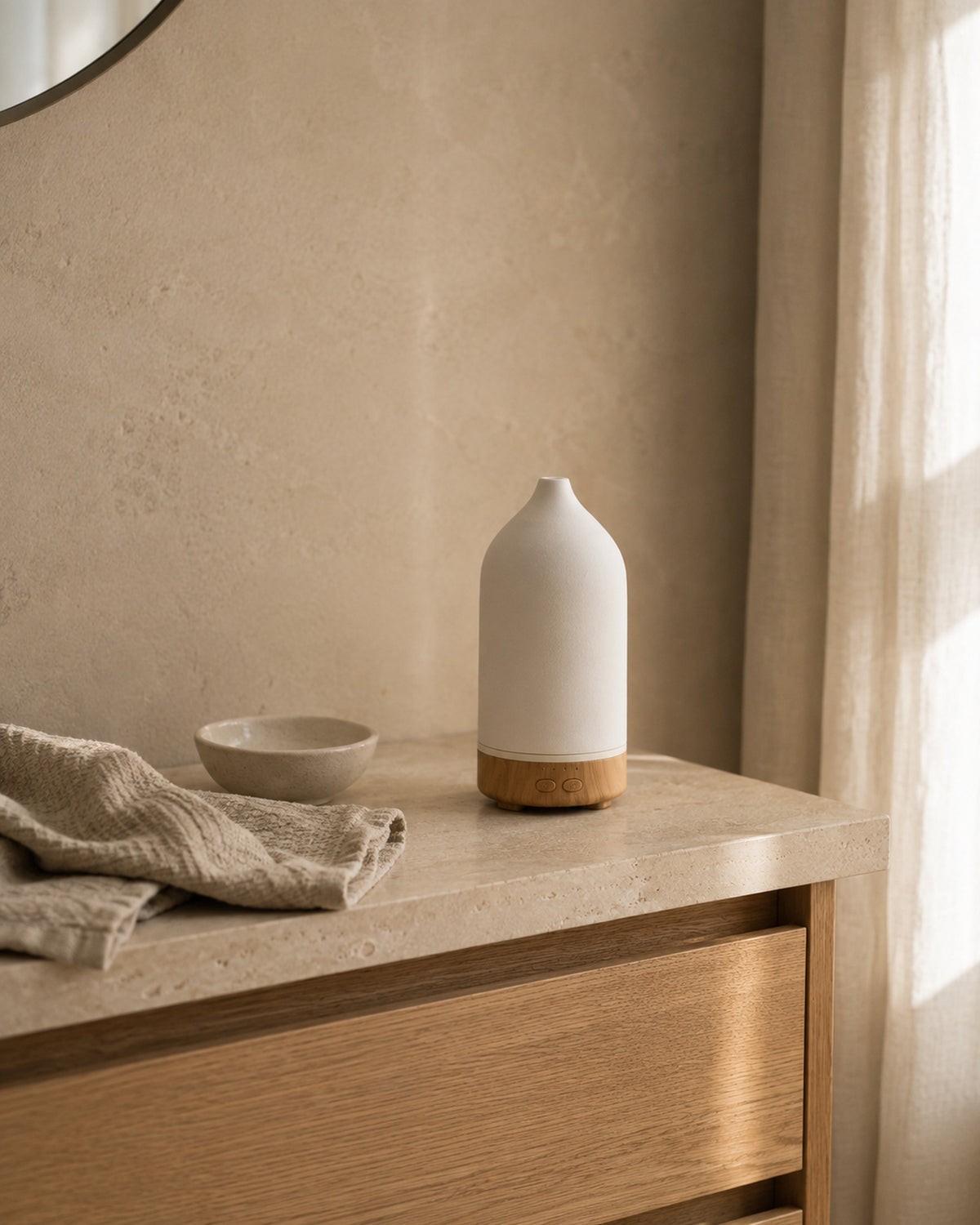 The diffuser on a stone bathroom counter beside a folded linen towel